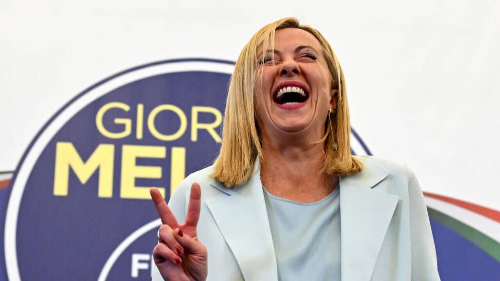 Giorgia Meloni fa il segno della vittoria mentre ride in modo sguaiato